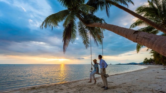 A couple on a palm-tree swing over the beach at Na Thon on Ko Samui